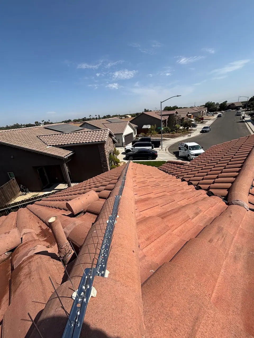 Bird deterrent strips following the ridge of a red tile roof