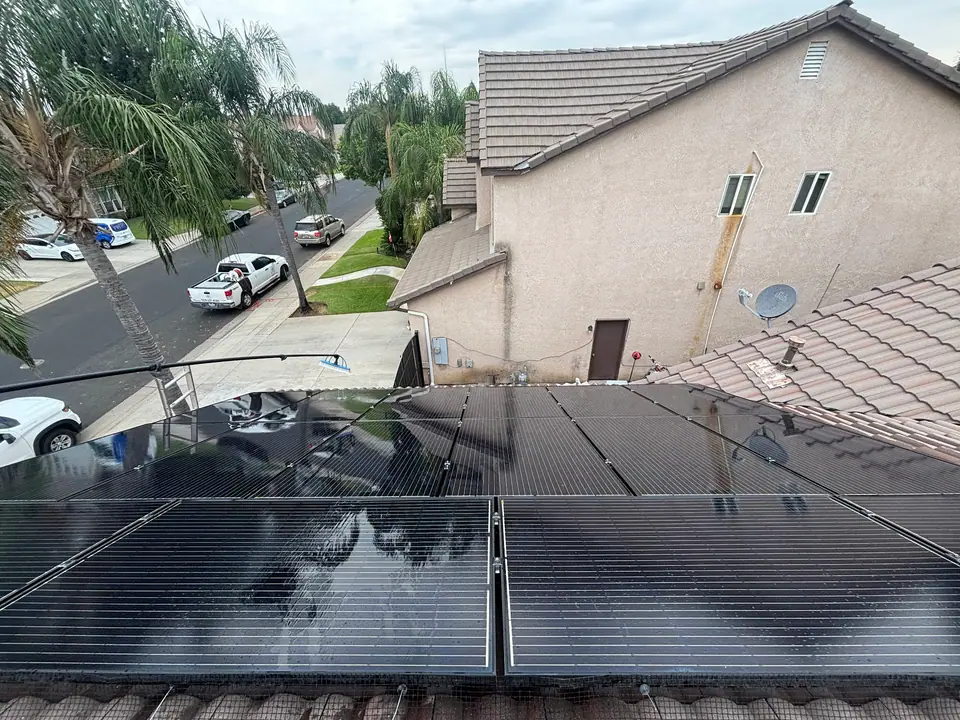 Clean reflective solar panels beside a residential tile roof