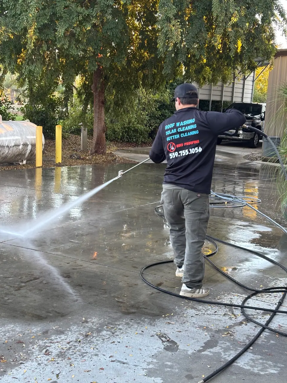 Technician using a pressure washer on outdoor concrete paving