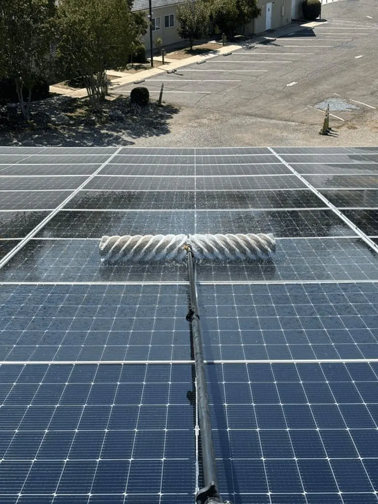 Rooftop solar panel rows with a cleaning brush across the glass