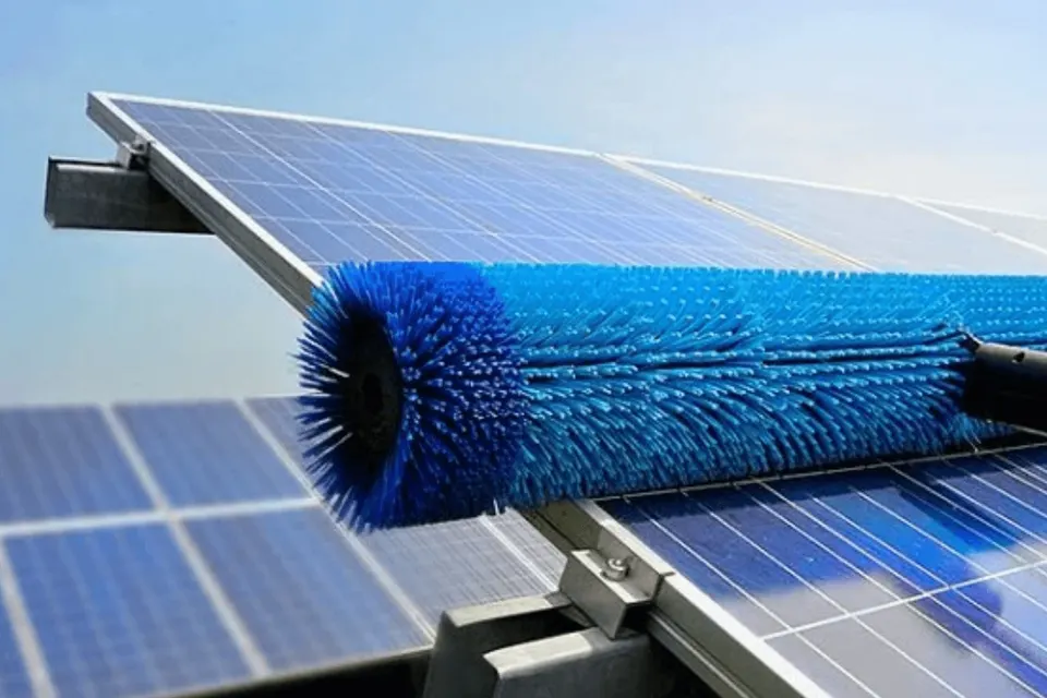 Blue soft brush washing the glass surface of rooftop solar panels